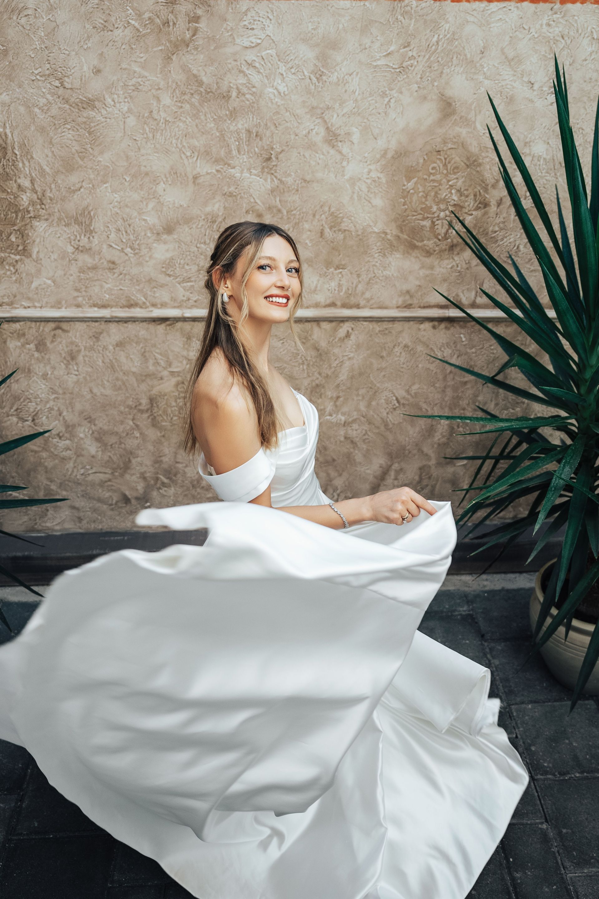 Stunning bride twirls joyfully in a fashionable outdoor setting, captured with dynamic motion.